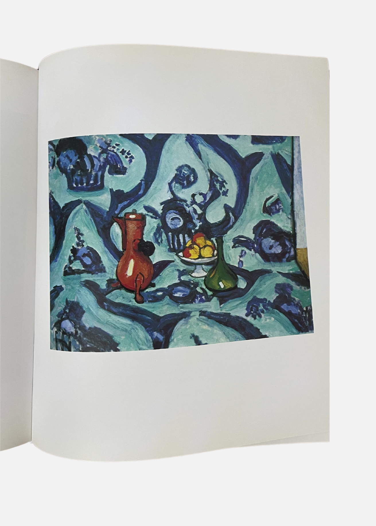 Un livre ouvert présentant une peinture d'une table bleue et blanche, œuvre de Matisse.